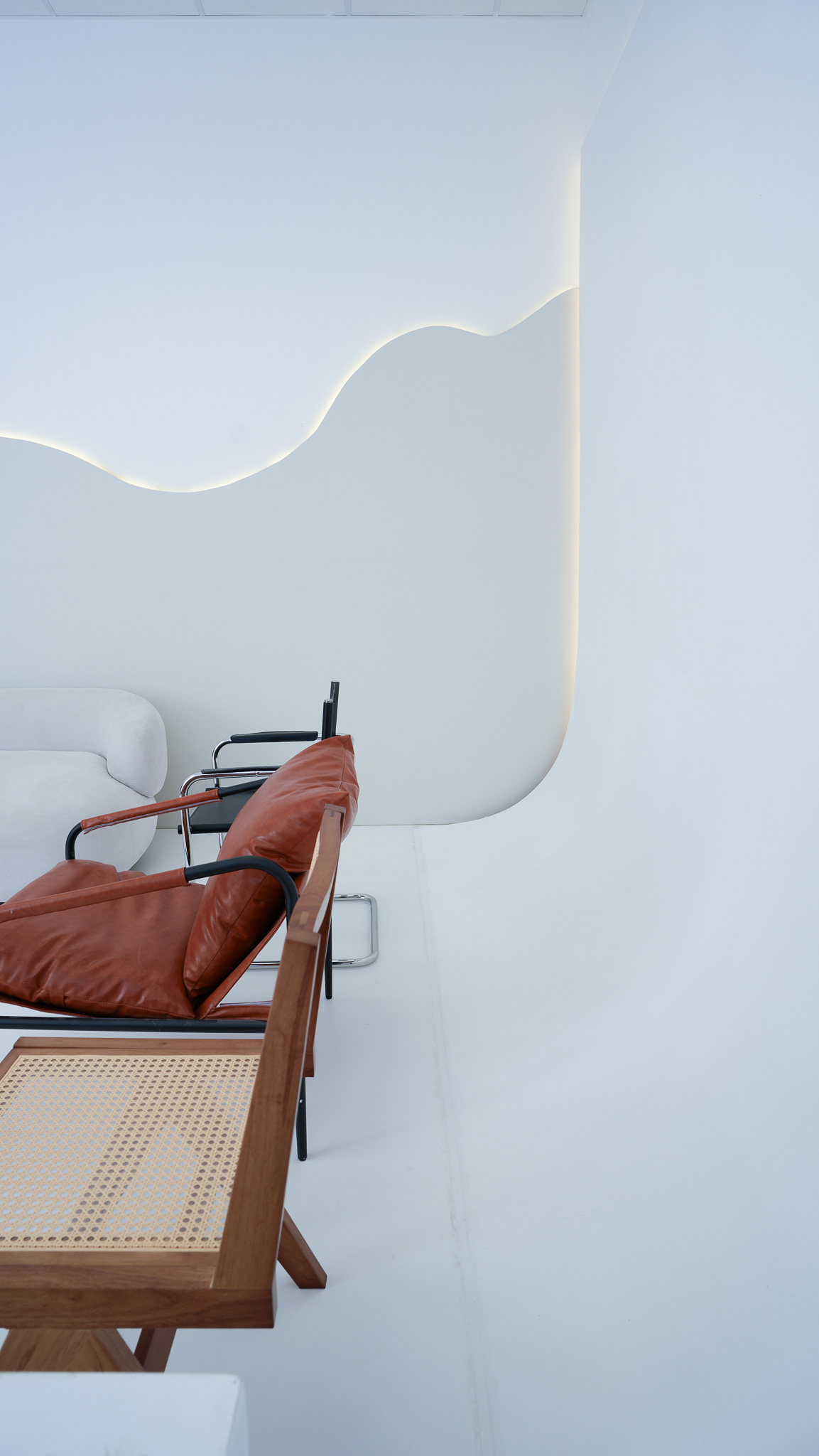 Zyklorama mit geschwungenem LED-Wandlicht und Designmoebeln