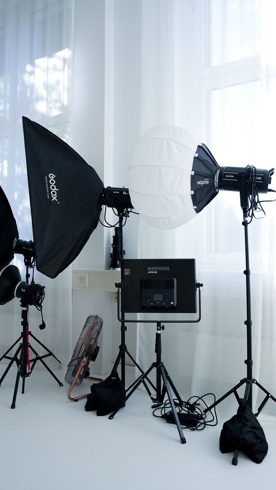 Godox-Leuchten mit Softbox und Laterne, ein Neewer-Panel und ein Kupfer-Ventilator vor dem Fenster