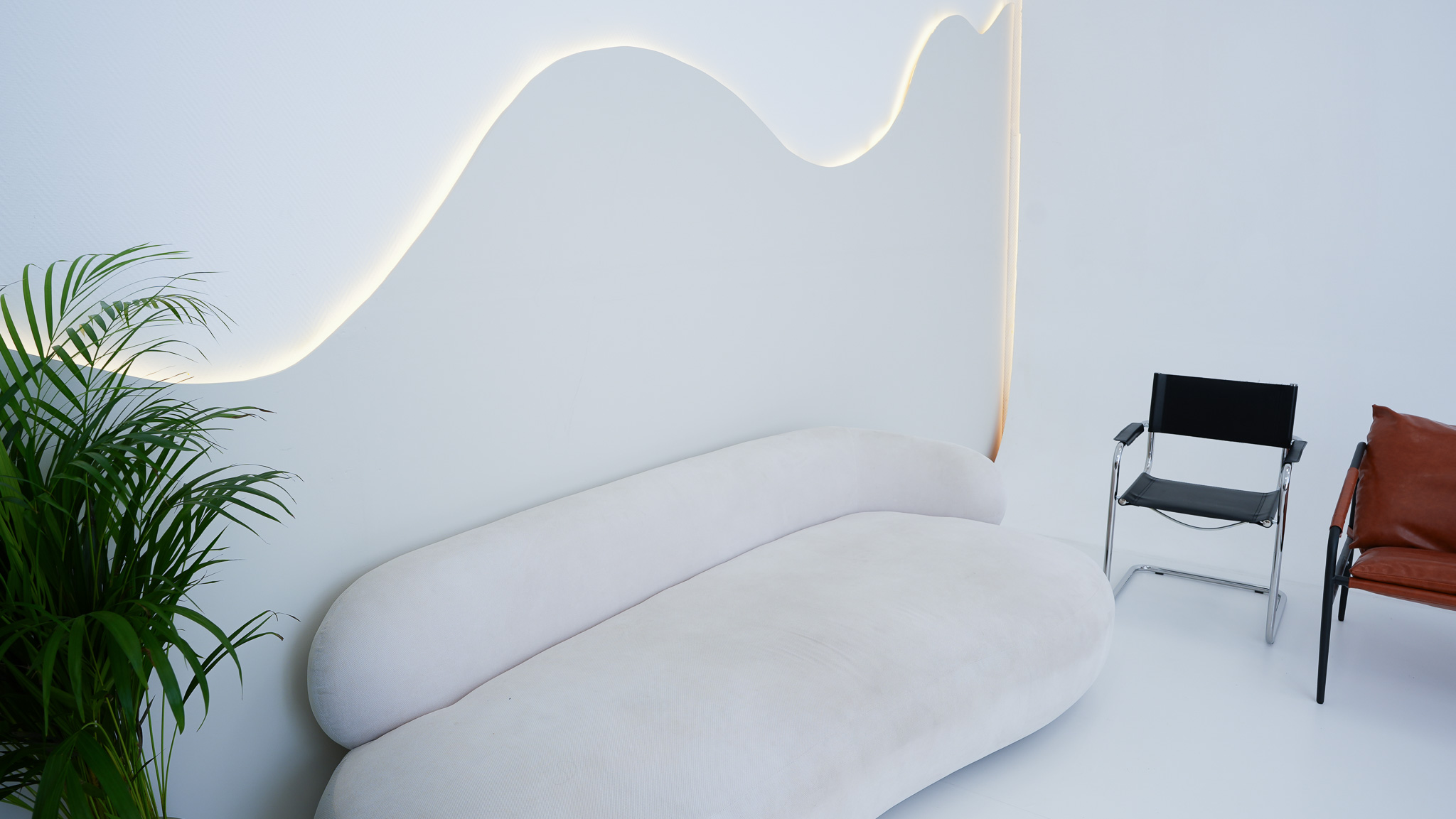 Sofa-Insel mit Pflanze und geschwungenem Wandlicht