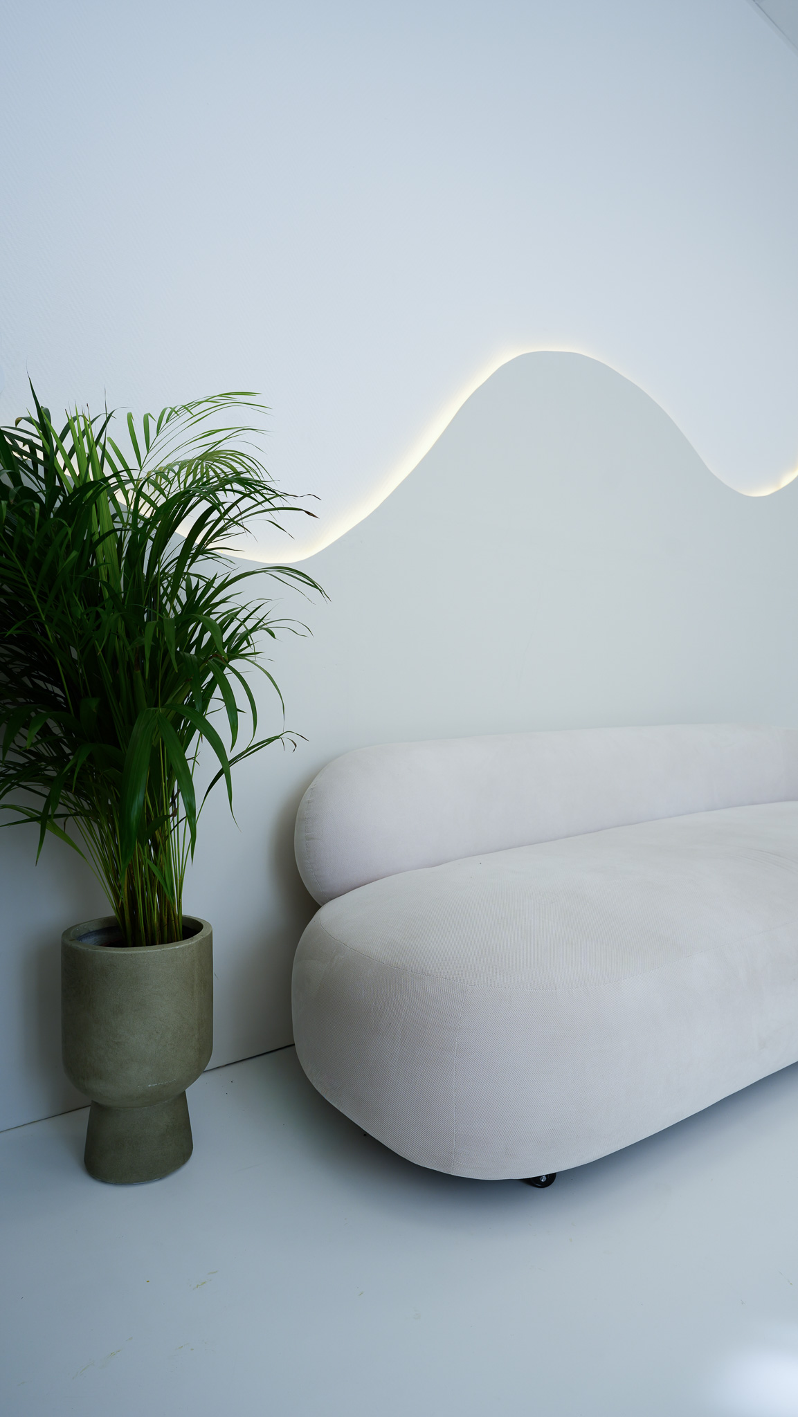 Studioraum mit Sofa und geschwungenem Wandlicht